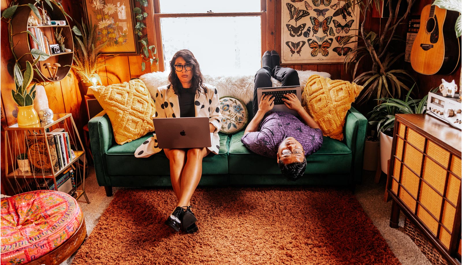 Jess and Nelson sitting on a couch with their laptops